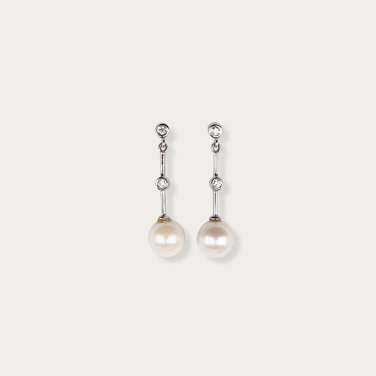 Linea Earrings in 14k white gold with bezel-set diamonds leading to 7mm freshwater pearls, 1-inch drop, post back closure.